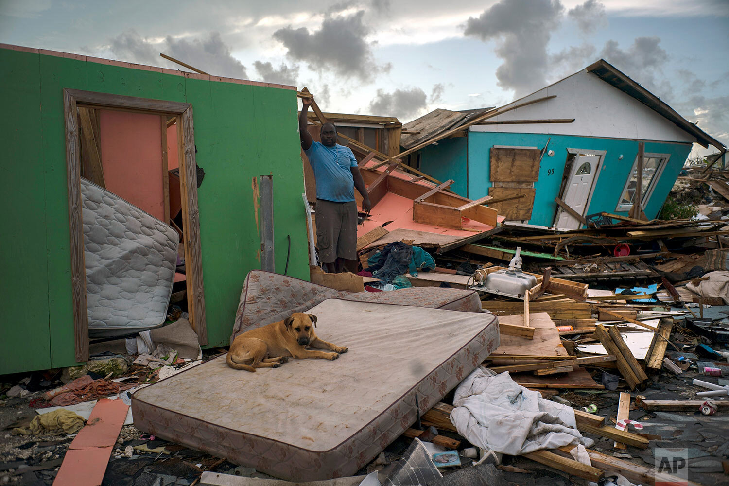  A man stands next to a destroyed house as a dog named Francoise rests on a mattress in the rubble left by Hurricane Dorian in Abaco, Bahamas, Monday, Sept. 16, 2019. (AP Photo/Ramon Espinosa) 
