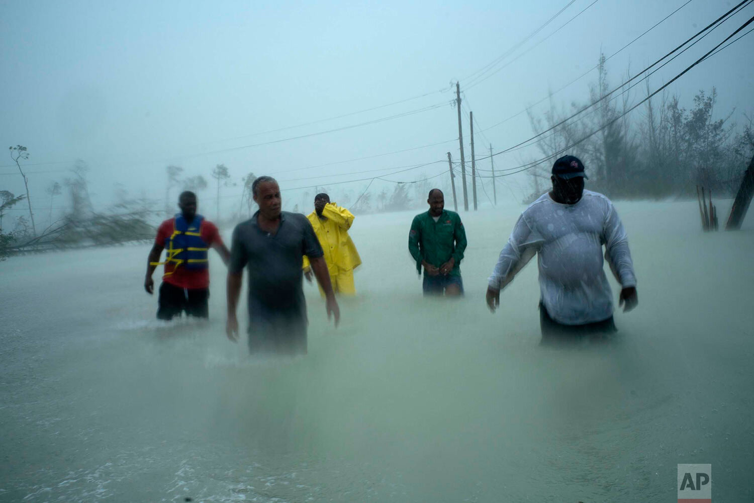  Volunteers walk under the wind and rain of Hurricane Dorian, on a flooded road after rescuing several families that arrived on small boats, near the Causarina bridge in Freeport, Grand Bahama, Bahamas, Tuesday, Sept. 3, 2019. (AP Photo/Ramon Espinos