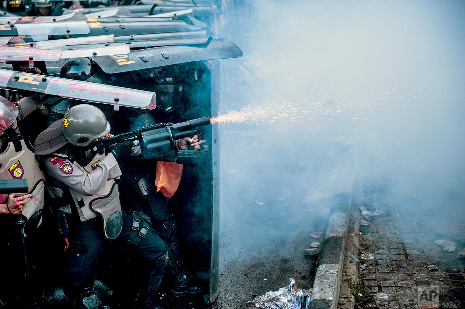 A police officer fires his tear gas launcher during a clash with student protesters in Bandung, West Java, Indonesia, Monday, Sept. 30, 2019. Thousands of Indonesian students resumed protests in several cities on Monday against a new law they say has crippled the country's anti-corruption agency, with some clashing with police. (AP Photo/Kusumadireza)