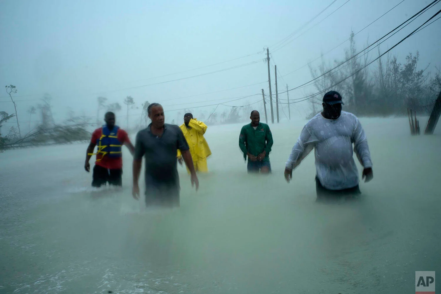 Volunteers walk under the wind and rain of Hurricane Dorian, on a flooded road after rescuing several families that arrived on small boats, near the Causarina bridge in Freeport, Grand Bahama, Bahamas, Tuesday, Sept. 3, 2019. (AP Photo/Ramon Espinosa)