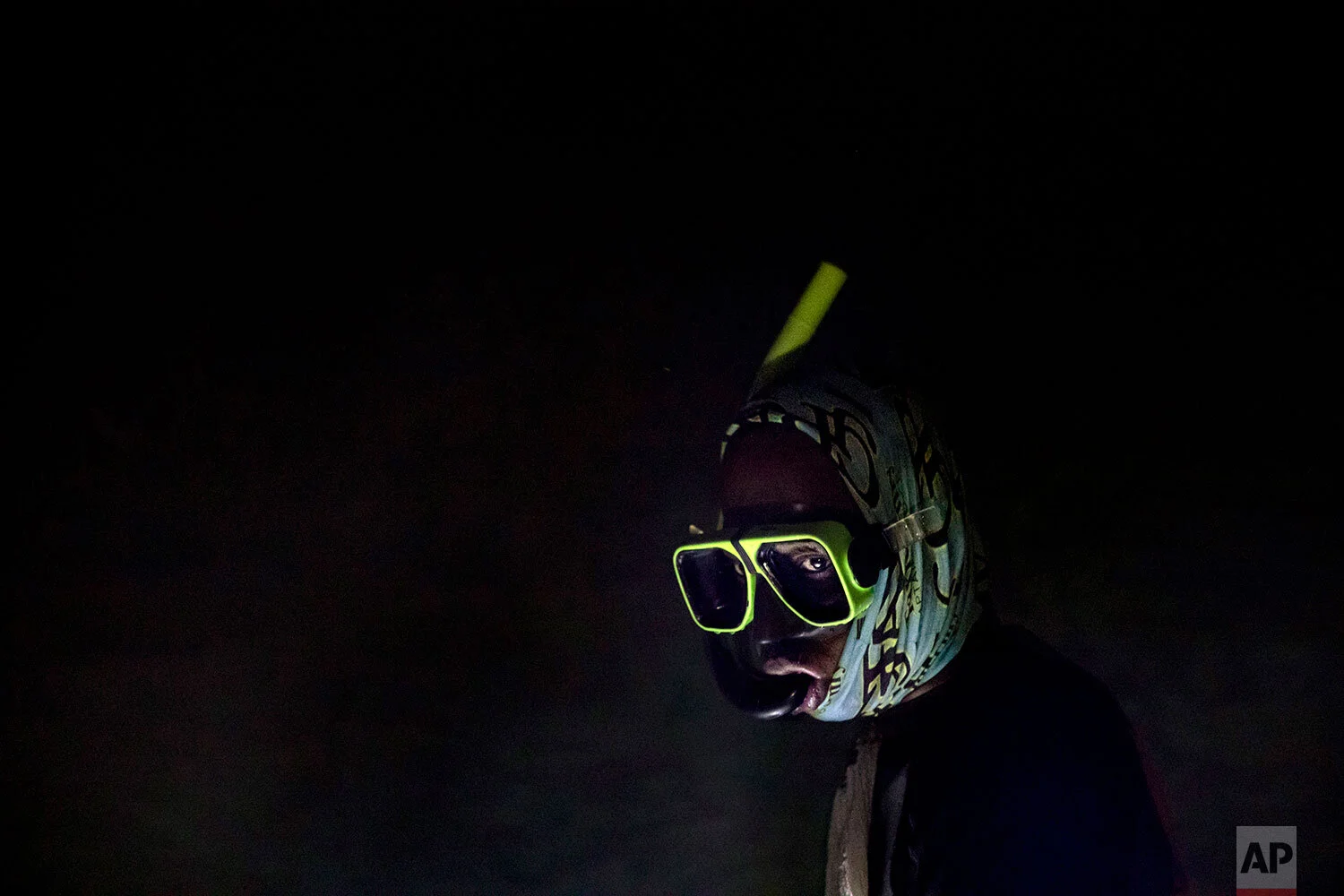 Nicholas Bingham enters the water to go night spearfishing, which is banned, especially in the sanctuaries set up to protect the island's endangered coral reefs and replenish fish stocks, in Stewart Town, Jamaica, Friday, Feb. 15, 2019. The restrictions have taken a toll on many Jamaicans' livelihoods, in a place where jobs can be scarce. In some places, fishermen have joined with local businesses to form marine associations and negotiate a no-fishing zone. But that simple line in the water must be enforced. (AP Photo/David Goldman)