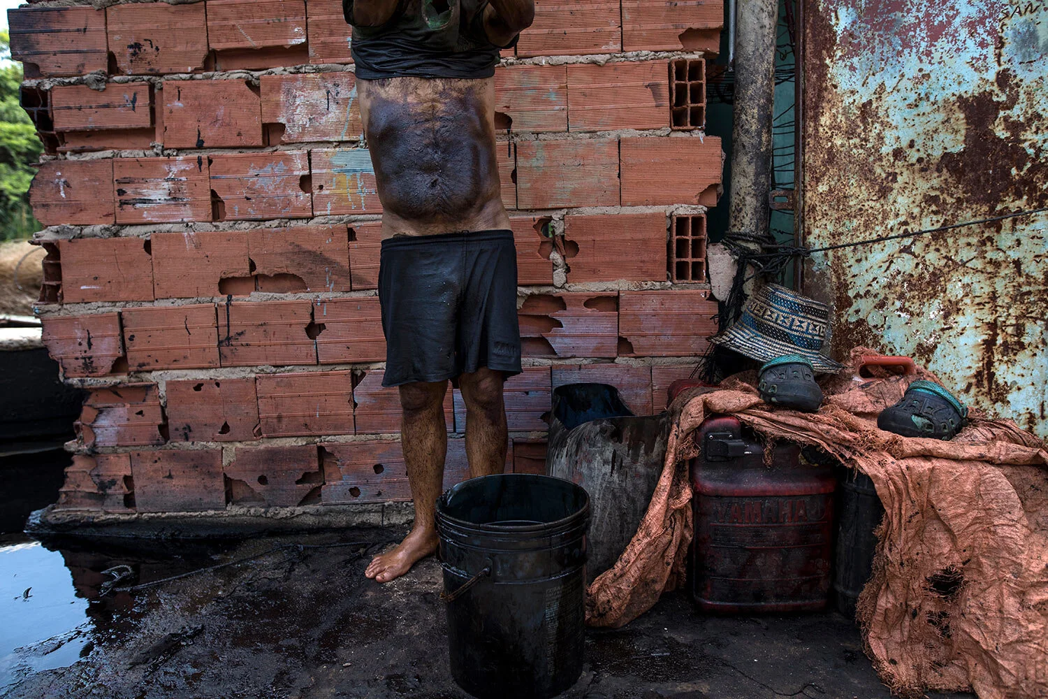 Fisherman Manuel Nune's stomach is covered in oil, as he cleans up after a day of crab fishing on Lake Maracaibo in Cabimas, Venezuela, July 4, 2019. Fishermen wash the oil from their bodies with raw gasoline. They say the prickly rash in their skin is the price of survival. (AP Photo/Rodrigo Abd)