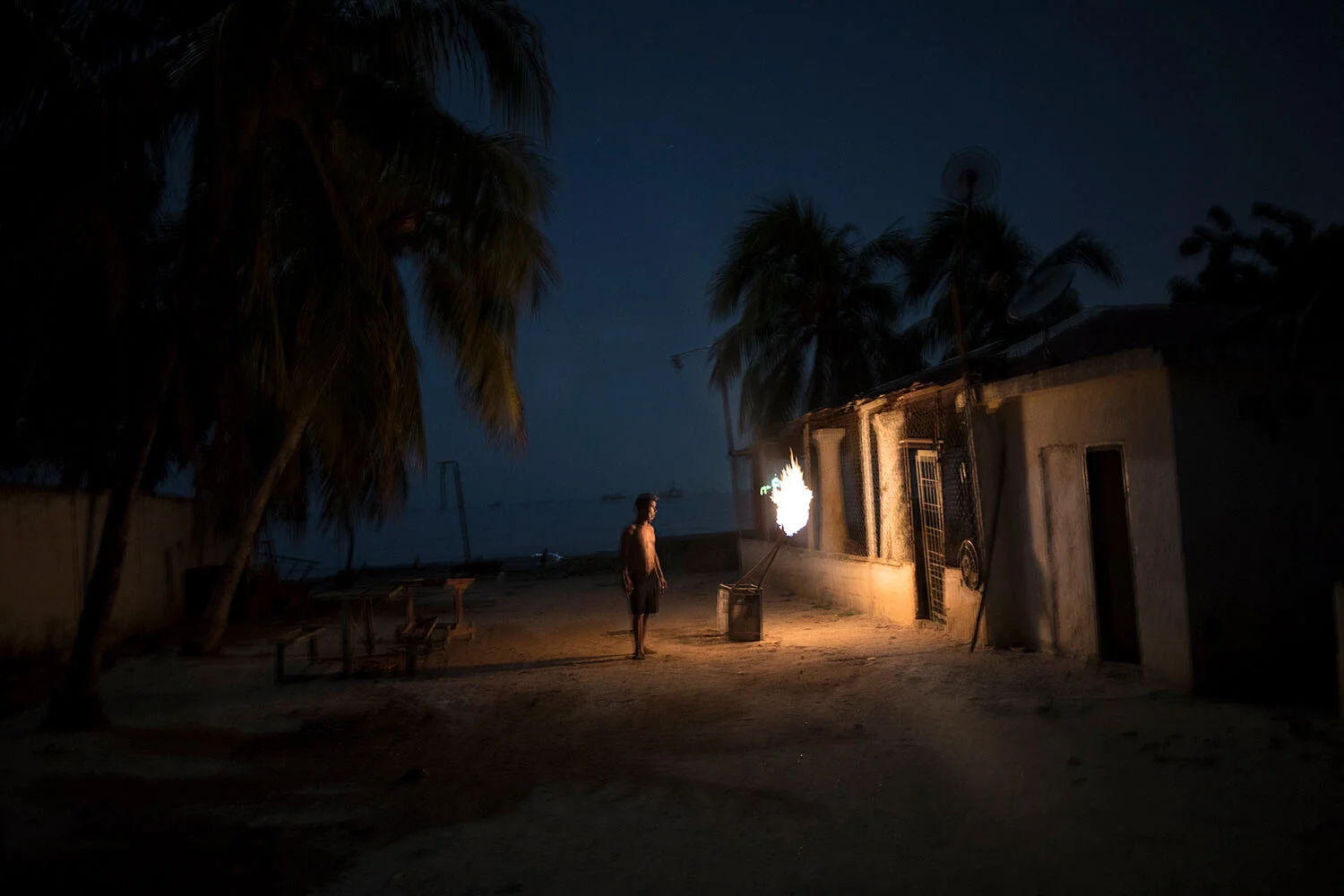 During a blackout, a man is illuminated by torches made out of crude oil, and known as "mechurrios," referring to the flares that burn excess gas on oil wells, in Cabimas, Venezuela, July 11, 2019. (AP Photo/Rodrigo Abd)