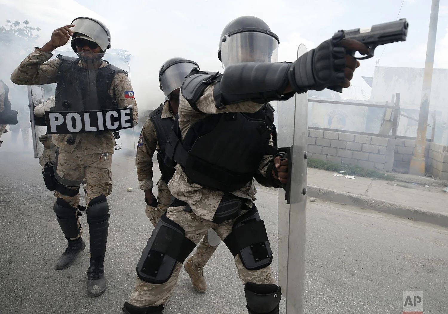 A police officer aims his weapon after demonstrators calling for the resignation of President Jovenel Moise broke through their lines, in Port-au-Prince, Haiti, Friday, Oct. 4, 2019. (AP Photo/Rebecca Blackwell)