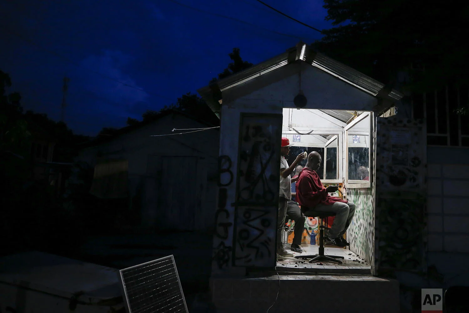 Barber Stanley Gustin, 29, finishes cutting the hair of a client in his shop across from the town square in Leogane, Haiti, Saturday, Oct. 5, 2019. (AP Photo/Rebecca Blackwell)