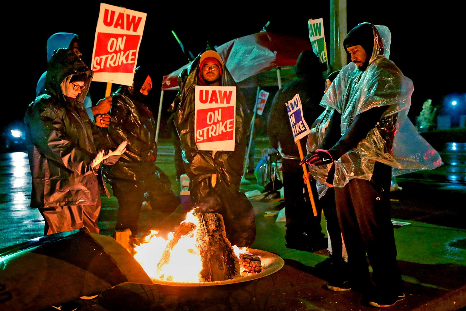 Third shift United Auto Workers stay warm by a fire as they picket outside gate 2 at the General Motors Wentzville Assembly Center in Wentzville, Mo., early Friday, Oct. 11, 2019. Tens of thousands of UAW workers have been on strike since Sept. 16, with both sides sparring over wages, job security, investments in U.S. plants and technology training for workers. (Laurie Skrivan/St. Louis Post-Dispatch via AP)