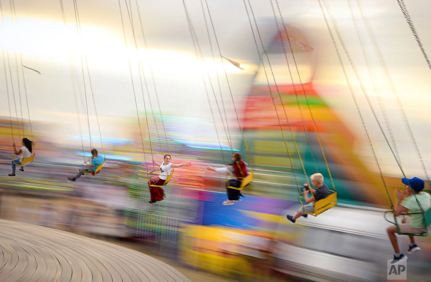 Shot with a slow shutter speed, people enjoy a swing ride at an autumn fair in Titu, southern Romania, Sept. 14, 2019. (AP Photo/Andreea Alexandru)
