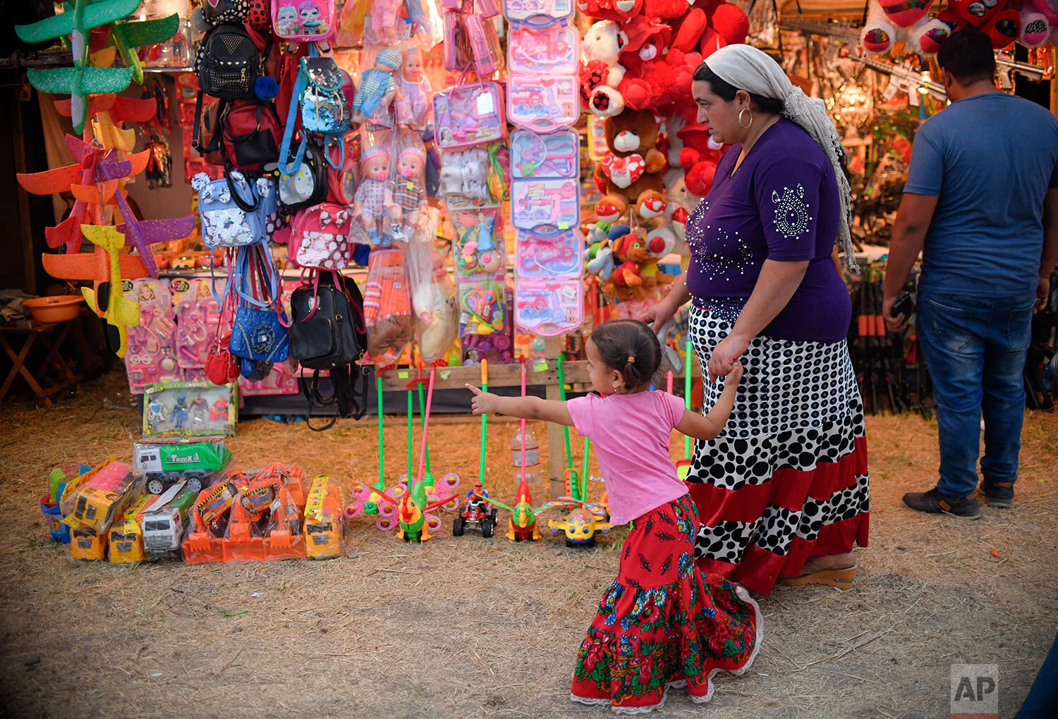 A little girl points to a toy stand at an autumn fair in Titu, southern Romania, Sept. 14, 2019. (AP Photo/Andreea Alexandru)