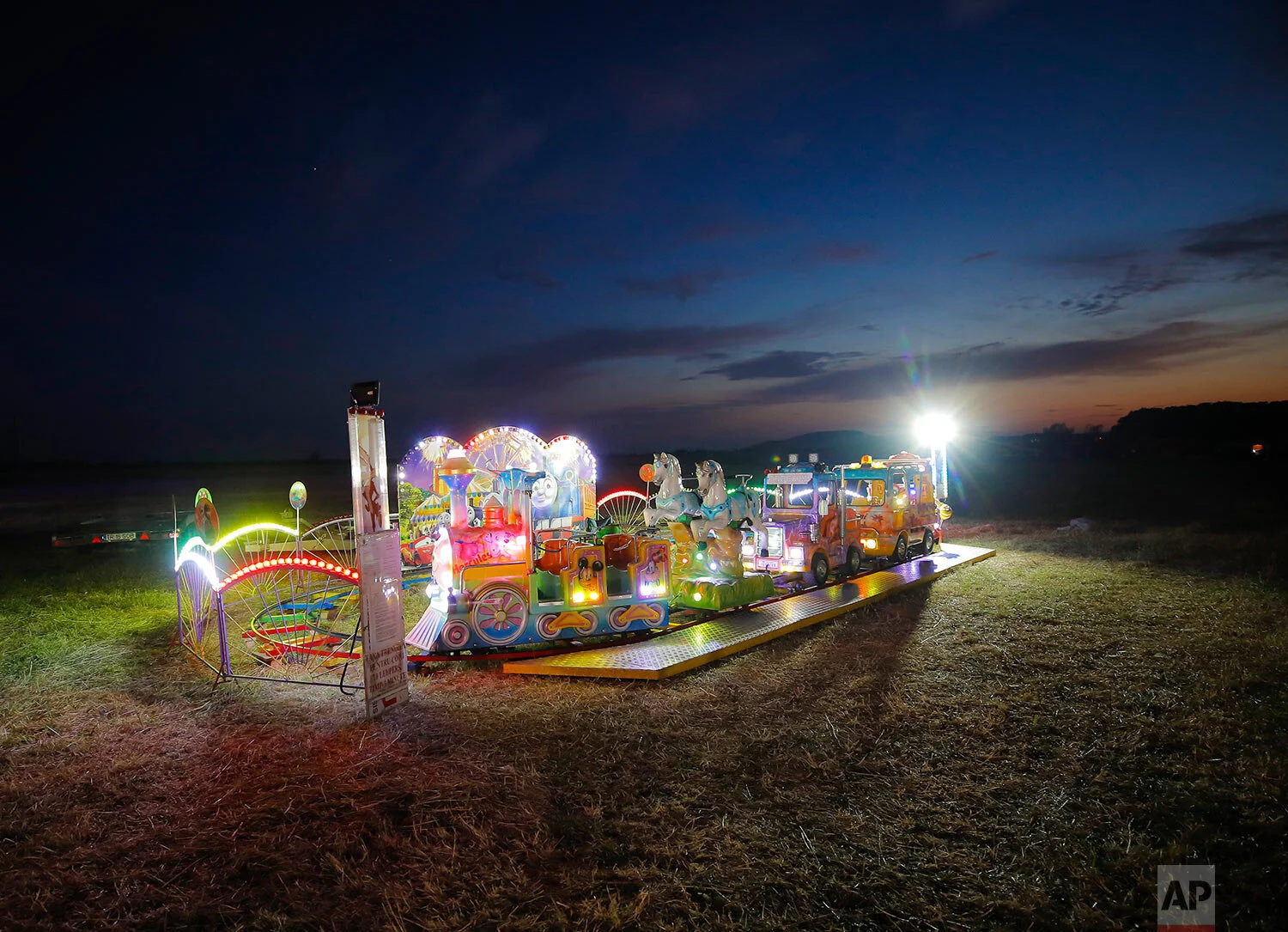 A ride is lit up before the start of an autumn fair in Titu, southern Romania, Sept. 12, 2019 (AP Photo/Vadim Ghirda)