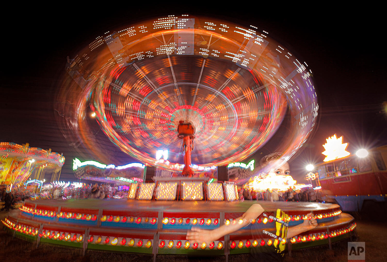 A child runs by a merry go round at an autumn fair in Rosiorii de Vede, southern Romania, Sept. 7, 2019. (AP Photo/Vadim Ghirda)