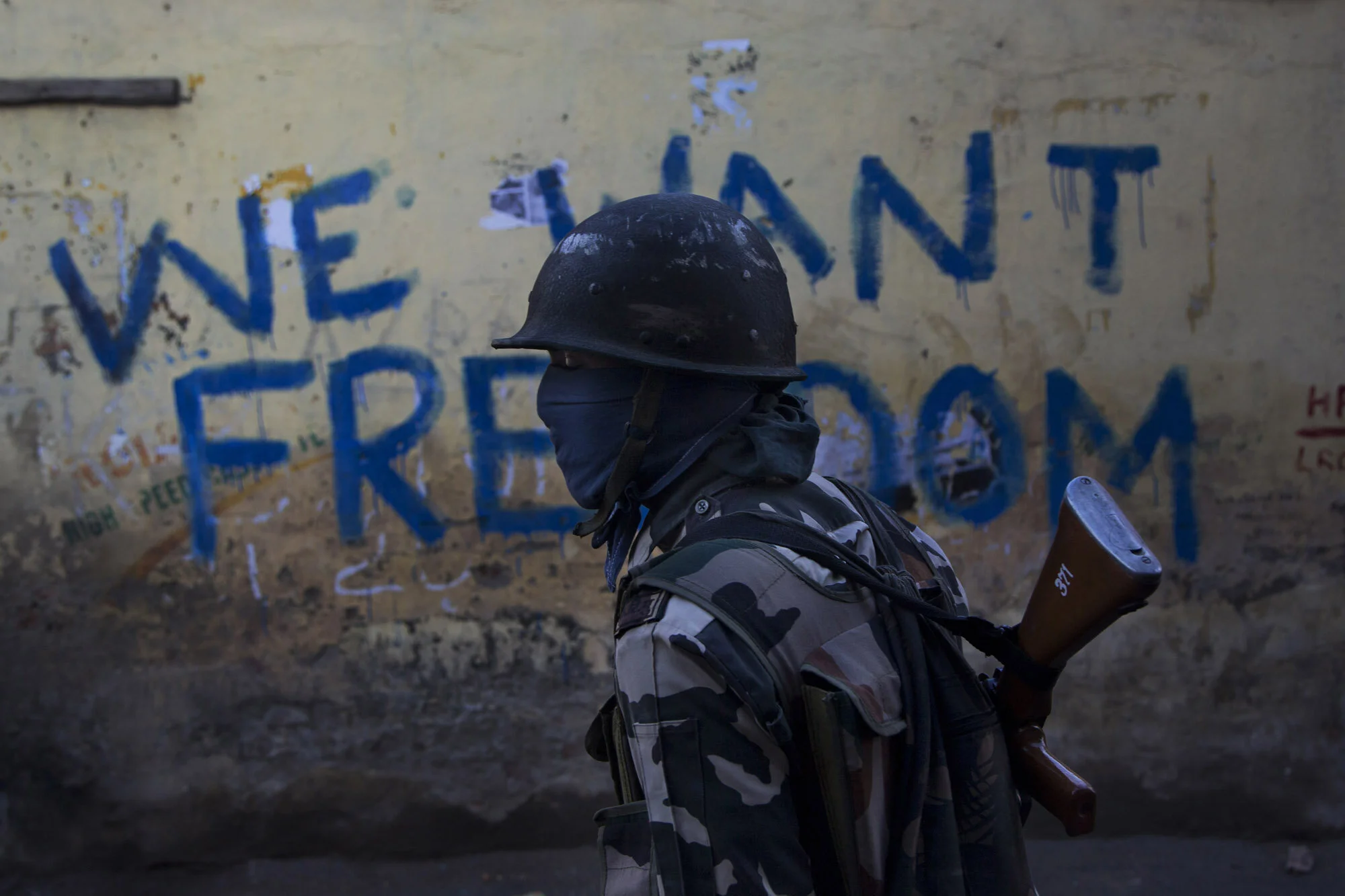 An Indian paramilitary soldier walks past graffiti on a wall in Srinagar, Indian-controlled Kashmir, Aug. 29, 2016.(AP Photo/Dar Yasin)