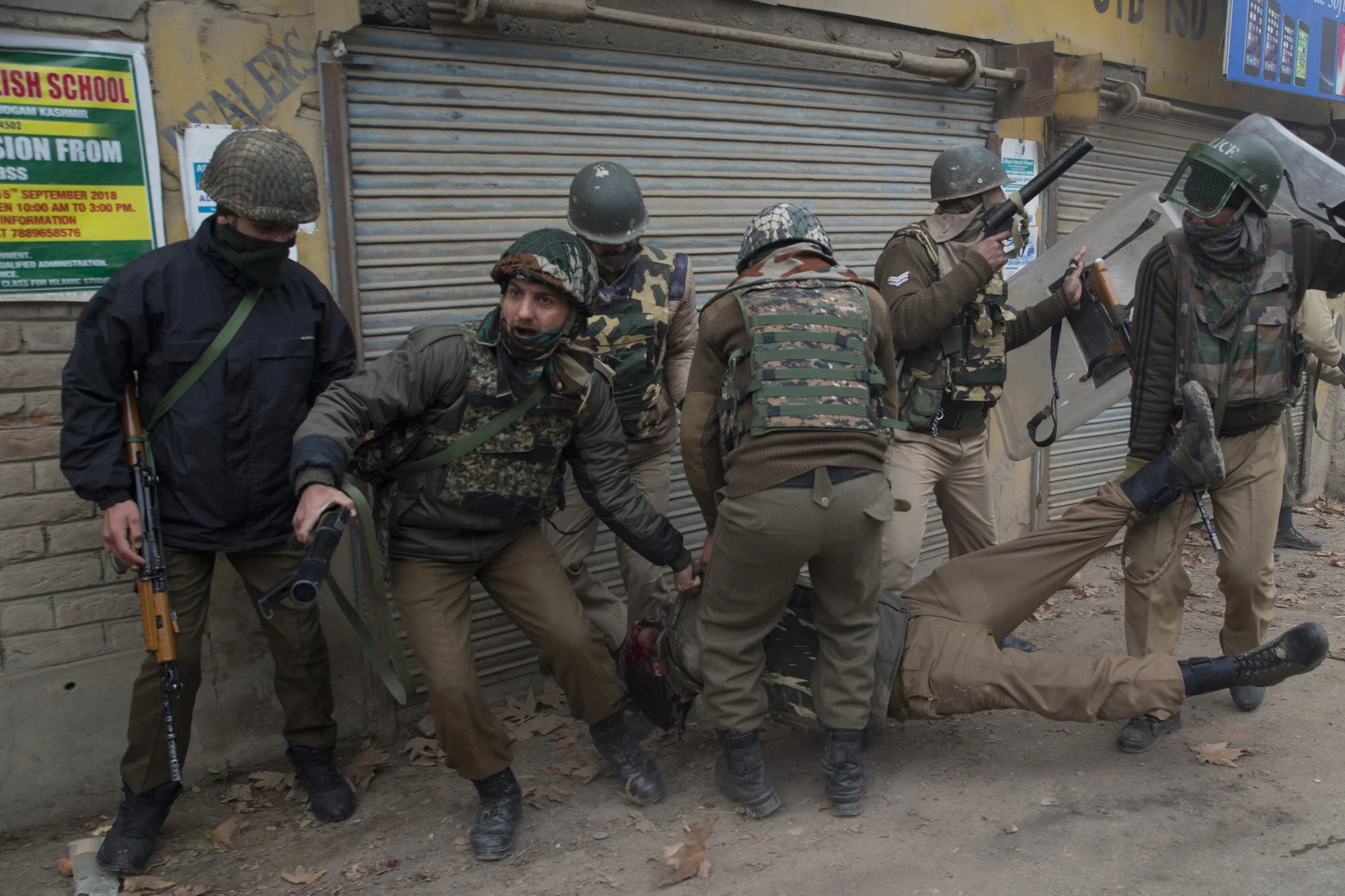 Indian paramilitary soldiers help their wounded colleague as he lies unconscious on the road after he was wounded during a protest near the site of gun battle in Chattergam area of Budgham 25 Kilometers from Srinagar, Indian controlled Kashmir, Nov. 28, 2018. (AP Photo/Dar Yasin)