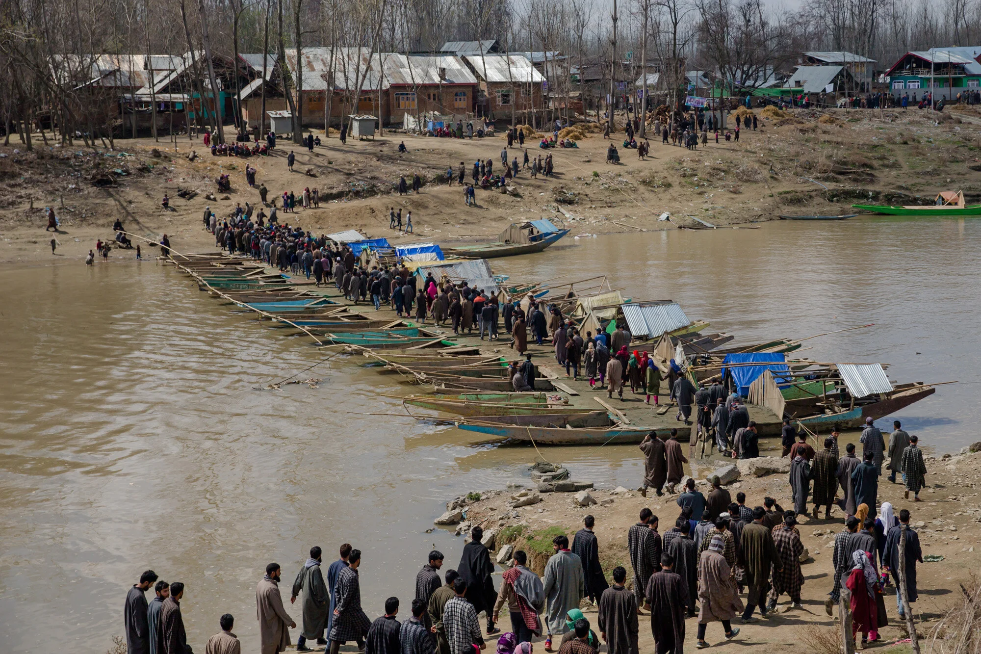 Kashmiri villagers cross a temporary bridge made by lining up boats to make way for people to cross a river to attend funeral of Shabir Ahmad, a suspected rebel in Awantipora, 30 kilometres (18 miles) south of Srinagar, Indian controlled Kashmir, March 16, 2018. (AP Photo/Dar Yasin)