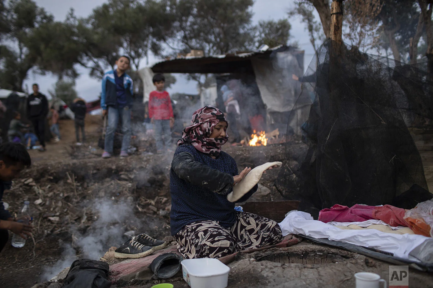 Pargoul Rahmani, 57, makes bread at a makeshift bakery in the overcrowded Moria refugee and migrant camp, Lesbos island, Greece, Tuesday, Oct. 8, 2019. (AP Photo/Petros Giannakouris)