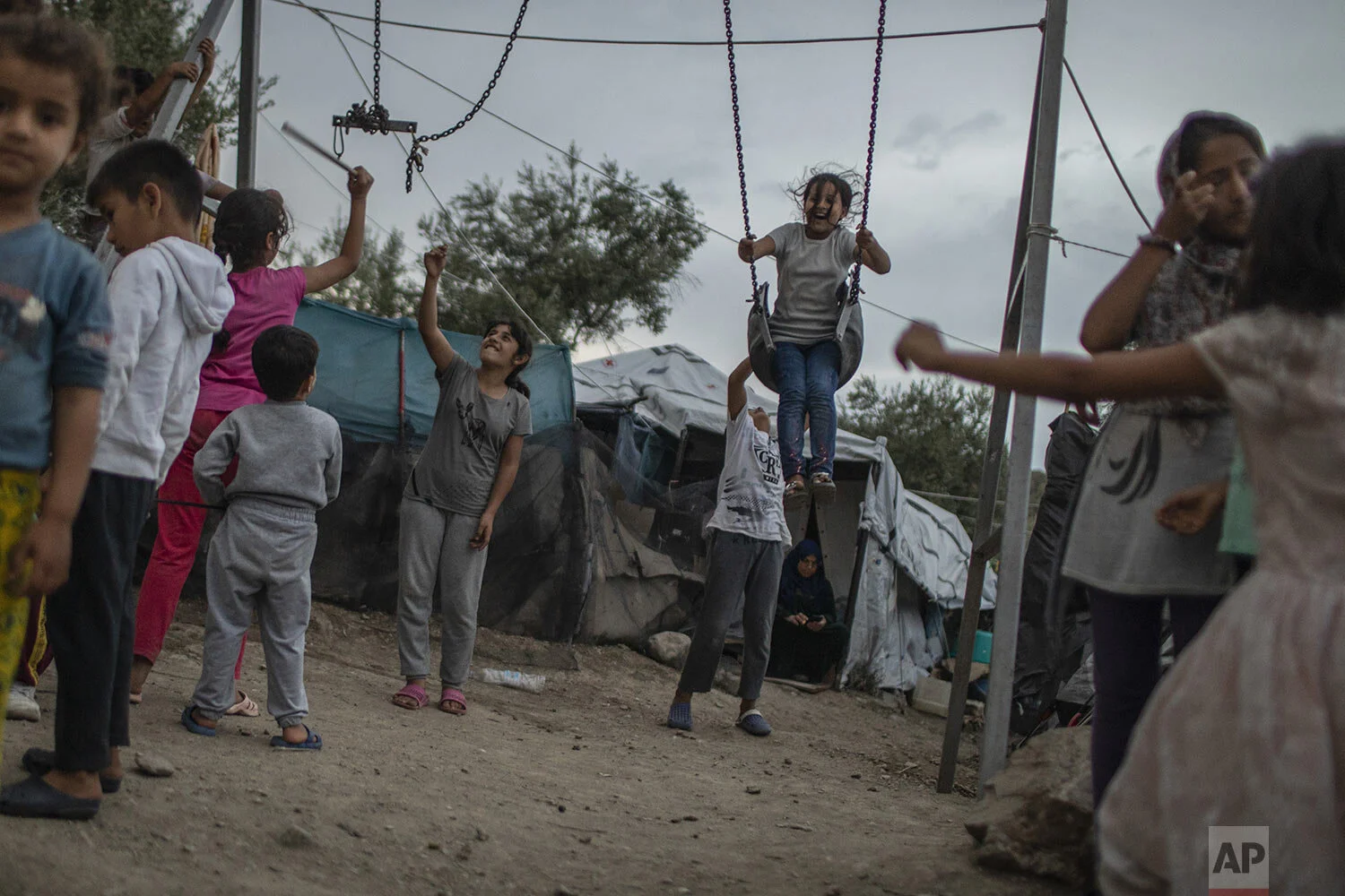 Children play near swings at the Moria refugee and migrant camp on the Greek island of Lesbos, Friday Oct. 4, 2019. (AP Photo/Petros Giannakouris)