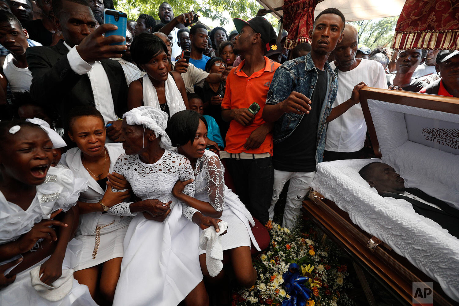  Family members grieve beside the coffin of one of the men killed during a month of demonstrations aimed at ousting Haitian President Jovenel Moïse, during a joint funeral for two victims in a public plaza near the National Palace in central Port-au-
