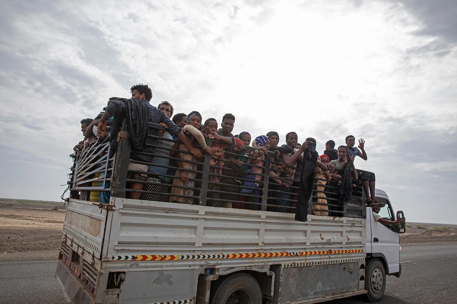 Ethiopian migrants who had just arrived in Yemen from Djibouti stand in the back of a pickup truck to be taken to desert compounds known in Arabic as "hosh," in Ras al-Ara, Lahj, Yemen. (AP Photo/Nariman El-Mofty)