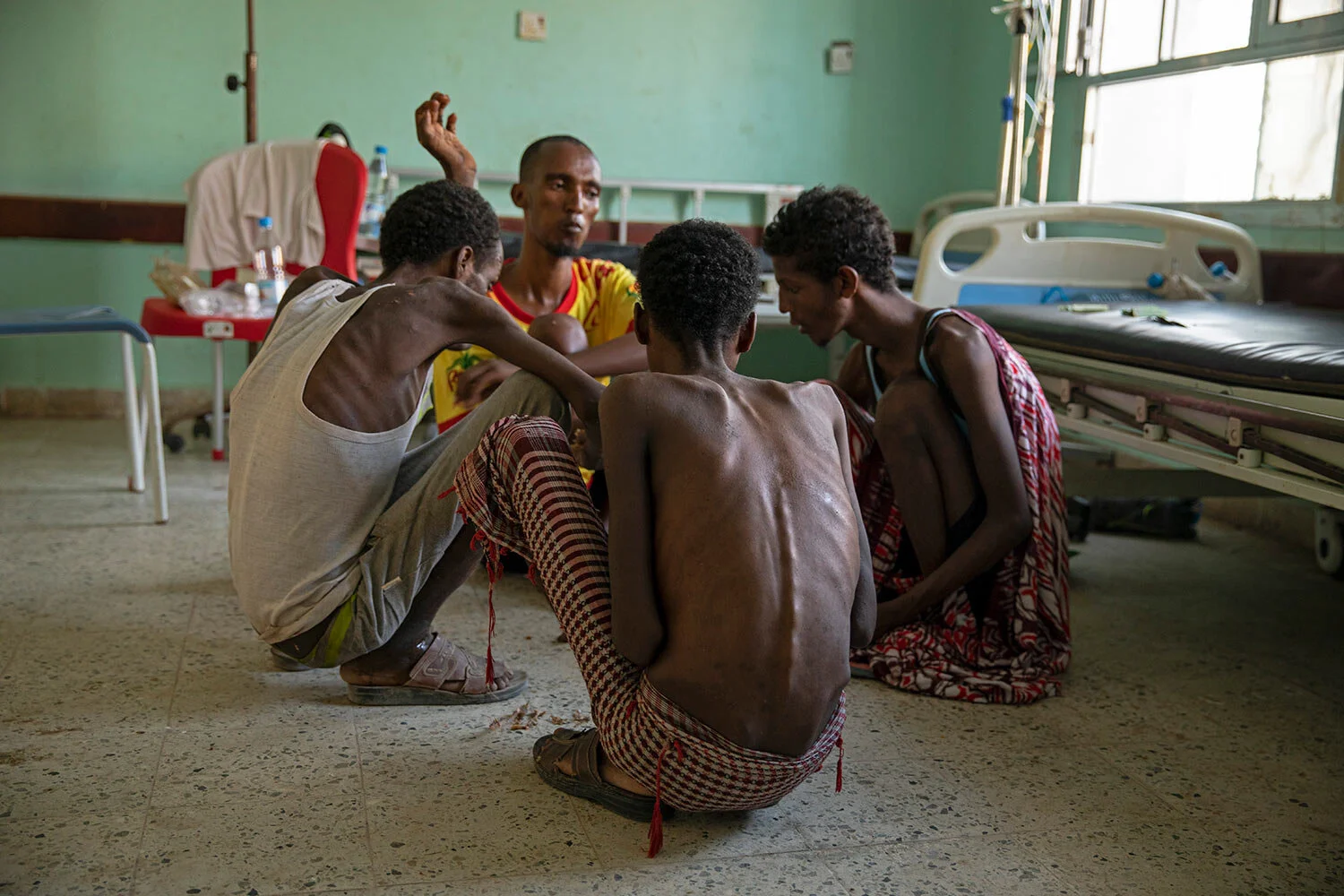 Ethiopian migrants, from center background to right, Gamal Hassan, Abdu Yassin, Mohammed Hussein, and Abdu Mohammed, who were imprisoned by traffickers for months, eat rice from a bowl on the floor, at the Ras al-Ara Hospital in Lahj, Yemen. They said they were fed once a day with scraps of bread and a sip of water when they were held. (AP Photo/Nariman El-Mofty)