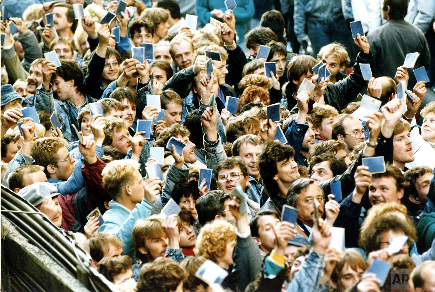  East German refugees wave while holding their travel documents in hands as they are about to enter the busses to take them to the special trains bound for West Germany in Prague, October 4, 1989. (AP Photo/Dieter Endlicher) 