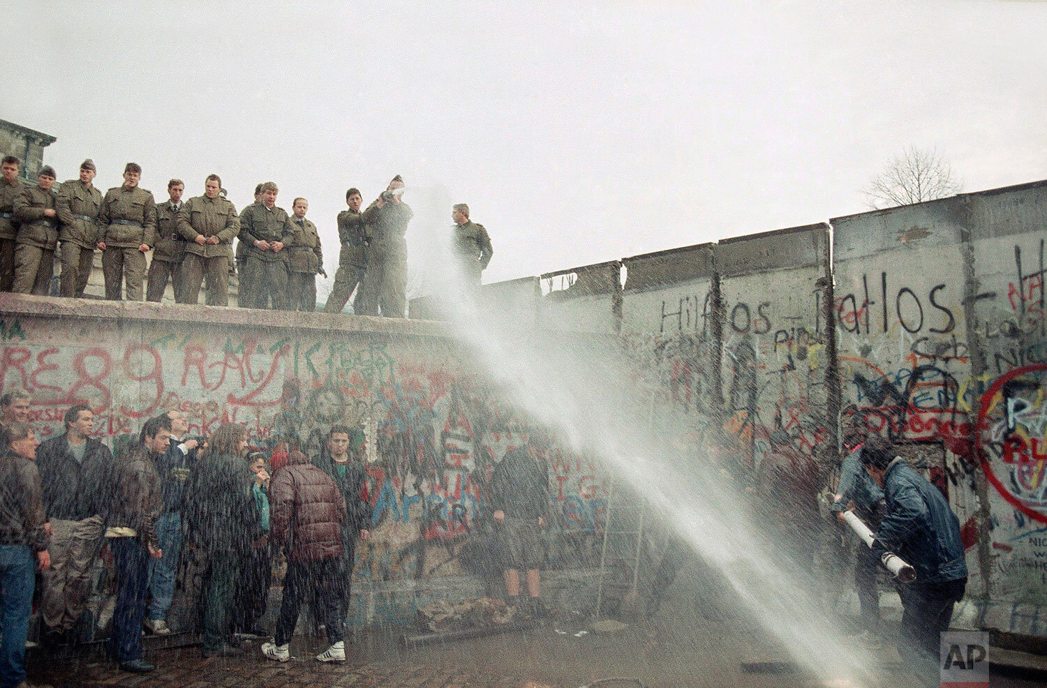  East German border guards use a hose to discourage West Berliners near Brandenburg Gate, in Berlin, Nov. 11, 1989, as citizens from the west tried to demolish the wall, demanding it be pulled down. (AP Photo/Lionel Cironneau) 