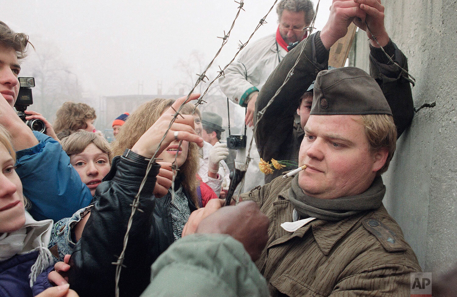  An East German border guard presents pieces of barbed wire he cut off the Berlin Wall at Ostpreussendamm passage in Berlin, Nov. 14, 1989. (AP Photo/John Gaps III) 