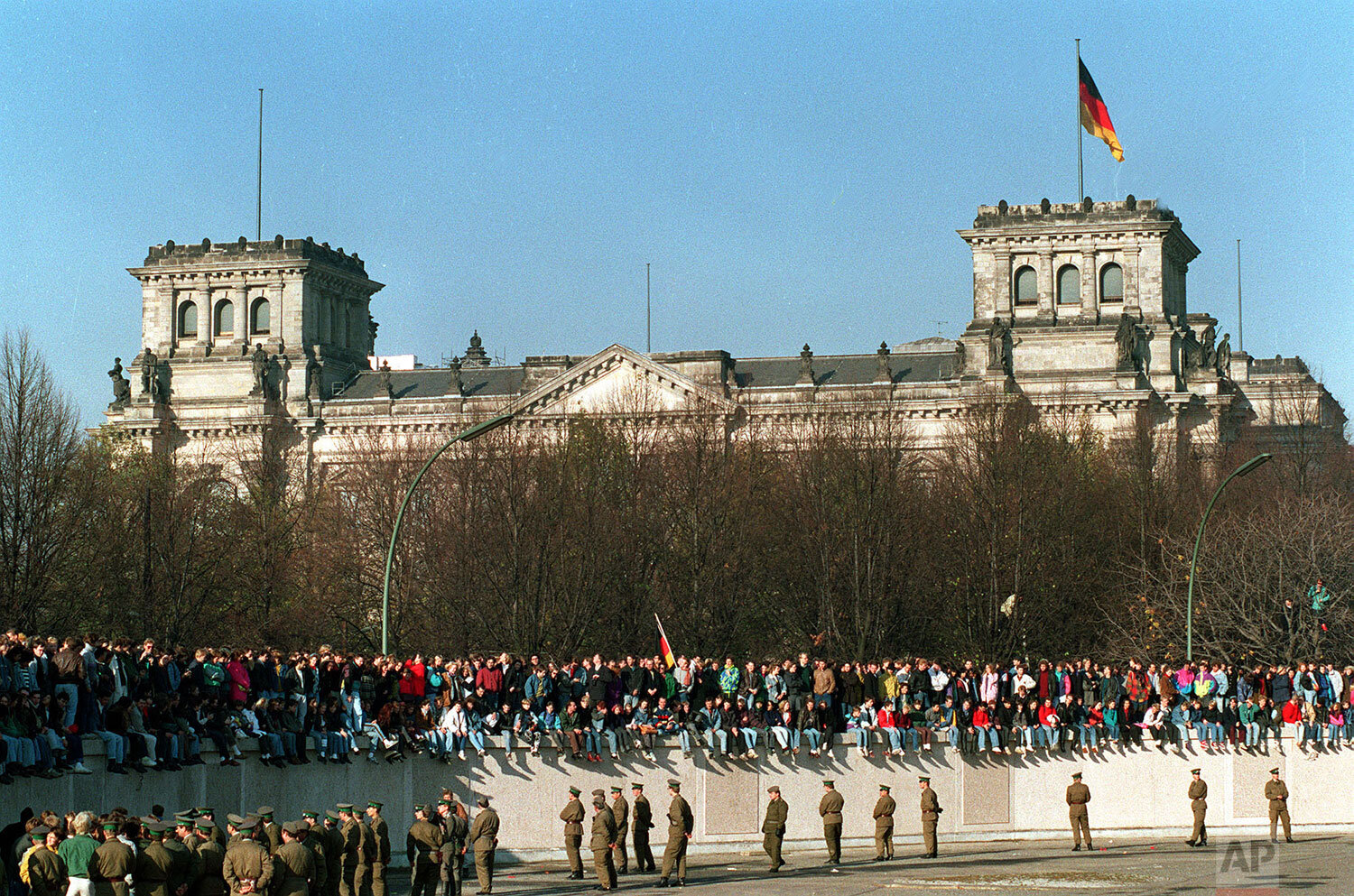  Germans from East and West stand on the Berlin Wall in front of the the Reichstag Building, Nov.  10, 1989, one day after the wall opened. (AP Photo) 