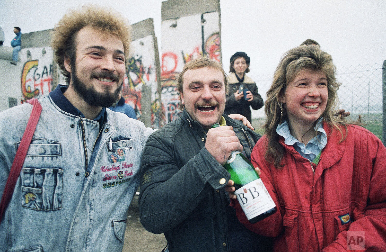  Bernd Mechelke of Ingolstadt, West Germany, welcomes his friends from Woltersdorf, East Germany with a bottle of champagne as they arrive in West Berlin, Nov. 12, 1989. (AP Photo/Thomas Kiezle) 