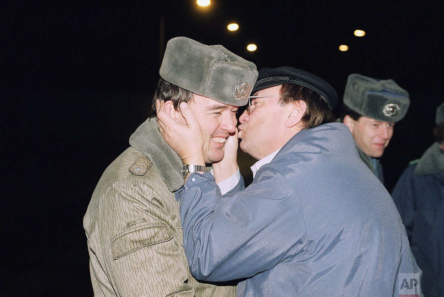  A West Berlin citizen holds the head of an East German border guard to kiss him after a new crossing point from East to West Berlin in the Zehlendorf district opened in Berlin, Dec. 11, 1989.  (AP Photo/Lutz Schmidt) 