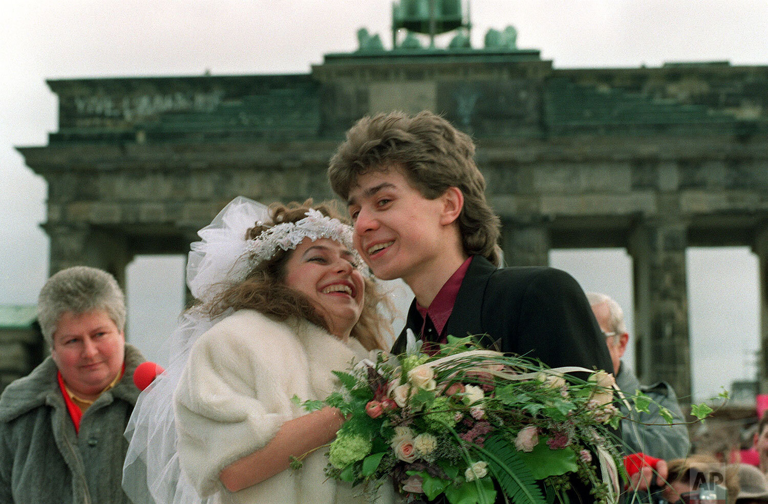  Barbara Hartung (21) from East Berlin and Oliver Matalla (21) from West Berlin smile happily after their wedding ceremony held in front of Brandenburg Gate, West Berlin, on Wednesday, February 14, 1990. (AP Photo/Rainer Klostermeier) 