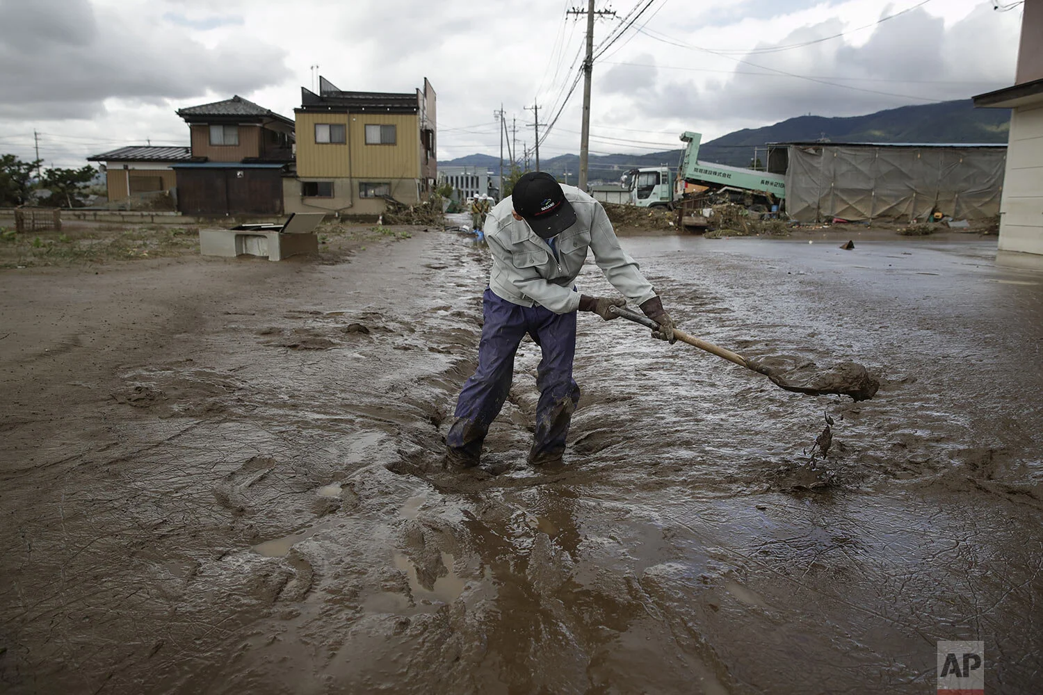 A man uses a shovel to scoop mud in a neighborhood devastated by Typhoon Hagibis Tuesday, Oct. 15, 2019, in Nagano, Japan. (AP Photo/Jae C. Hong)