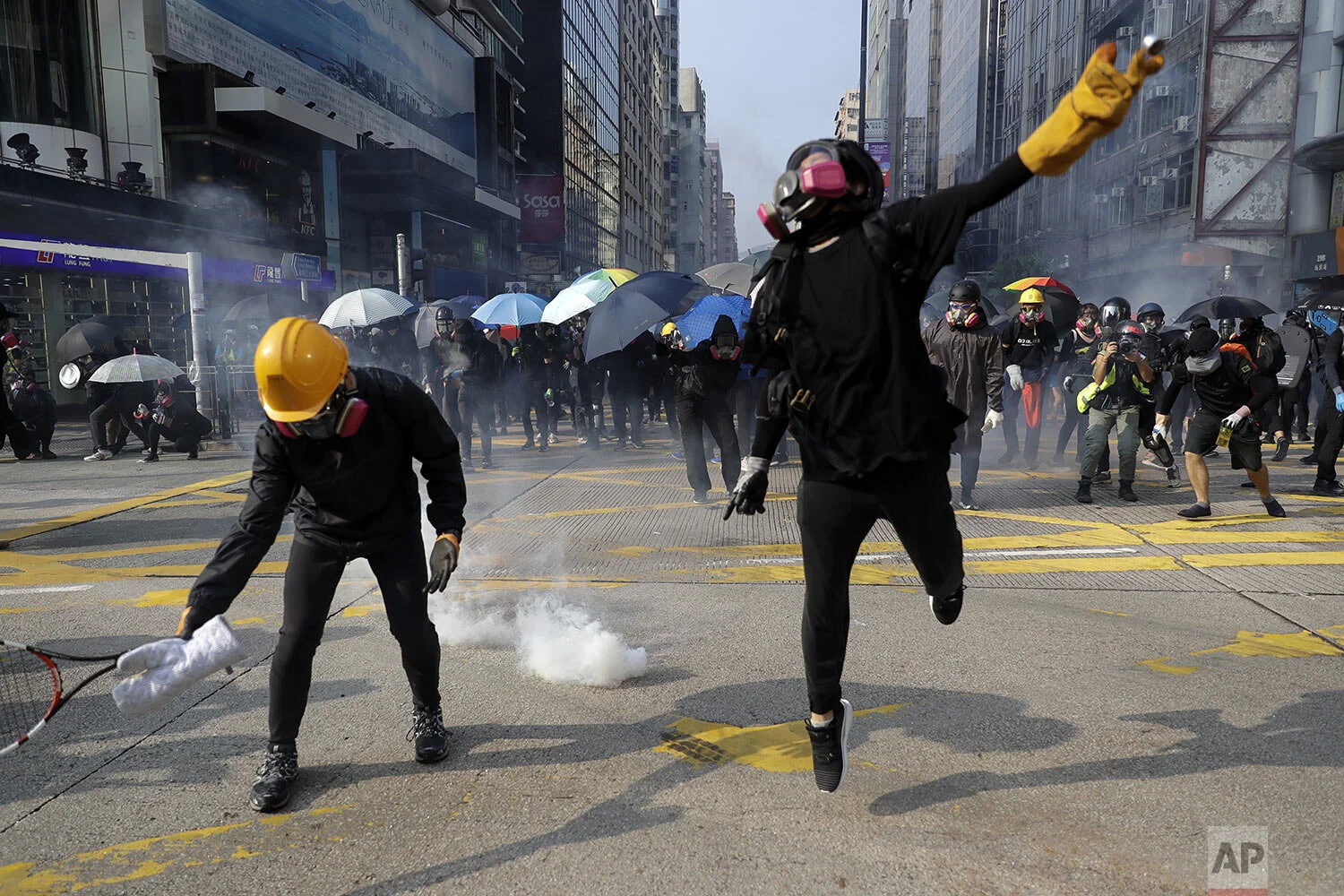Protesters throw tear gas canisters fired by riot policemen during a rally in Hong Kong, Sunday, Oct. 20, 2019. (AP Photo/Mark Schiefelbein)