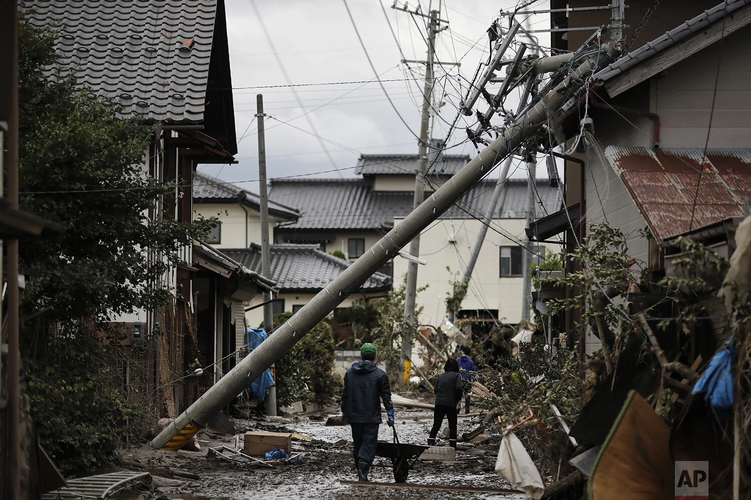 Residents walk along the mud-covered road in a neighborhood devastated by Typhoon Hagibis, in Nagano, Japan, Tuesday, Oct. 15, 2019. (AP Photo/Jae C. Hong)