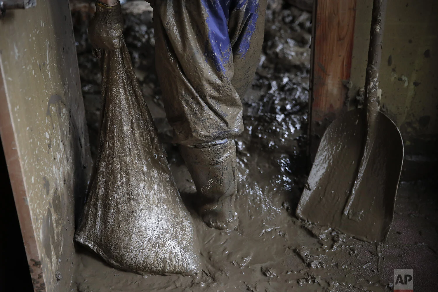 Masataka Murata carries a bag full of mud while cleaning up his friend's home damaged by Typhoon Hagibis Tuesday, Oct. 15, 2019, in Nagano, Japan. (AP Photo/Jae C. Hong)
