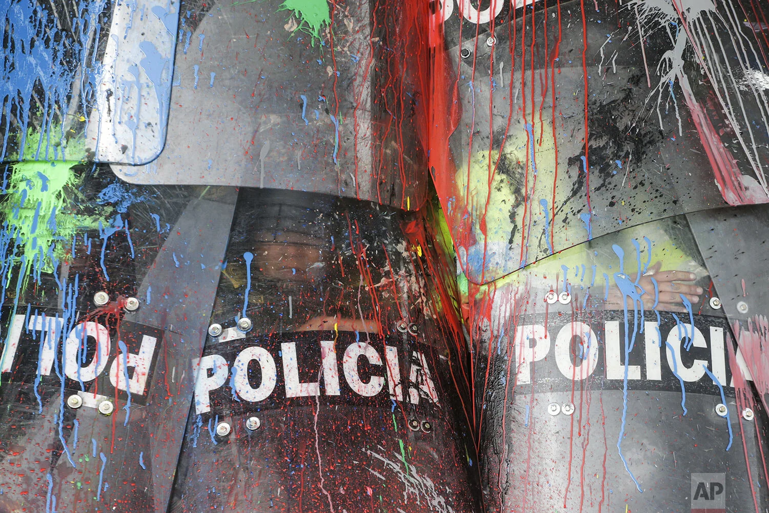 The shields of National Police are covered in paint thrown by protesting students in Bogota, Colombia, Thursday, Oct. 10, 2019. Students are demanding more government resources for education and higher quality universities. (AP Photo/Ivan Valencia)