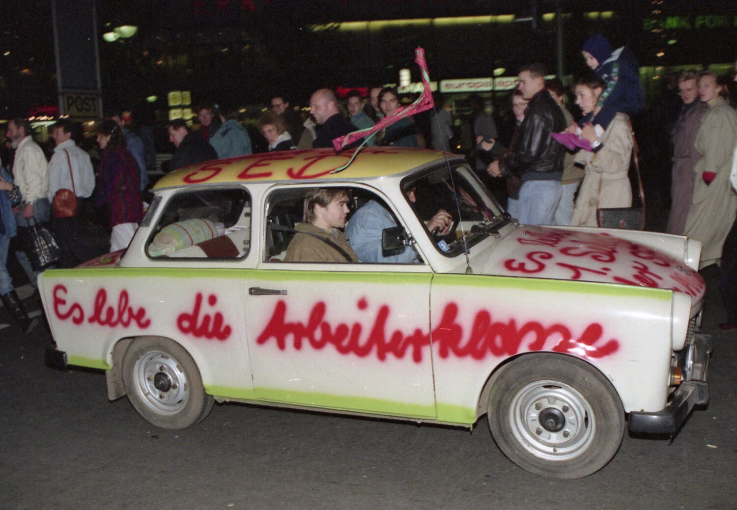 A Trabant car, made in East Germany, with a graffiti quote, “Shall the laboring classes live on” is pictured driving in West Berlin, West Germany, November 11, 1989, two days after the boarder between the two Germanys was abolished. (AP Photo)