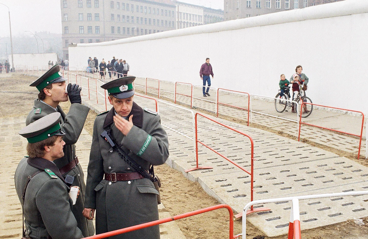 East German border guards have a coffee break atop of platform while looking down to just a few East German citizens moving into the west at Bernauer Strasse passage, in Berlin, Nov. 13, 1989. (AP Photo/Jockel Finck)