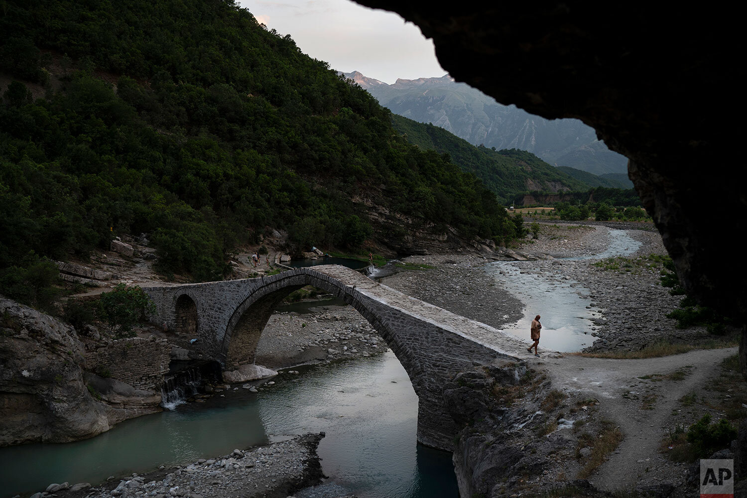  In this June 18, 2019 photo, a man crosses a bridge over the Langarica River, a tributary to the Vjosa near the city of Permet, Albania. Albania's government has set in motion plans to dam the Vjosa and its tributaries to generate much-needed electr