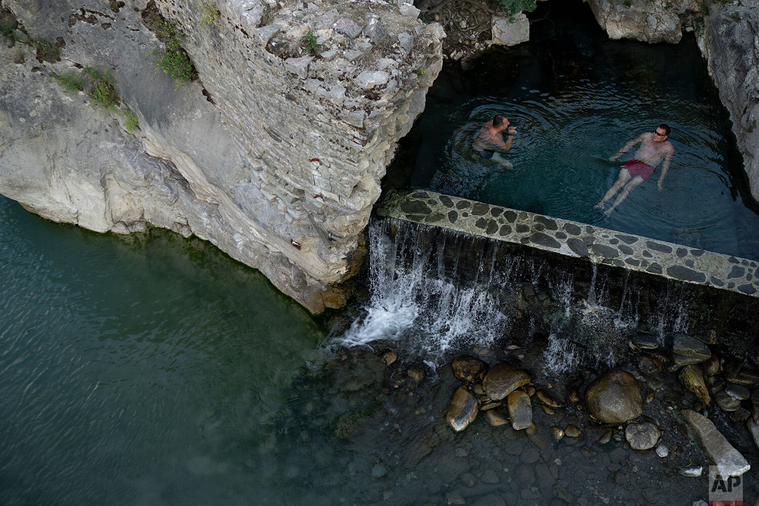  In this June 20, 2019 photo, people bathe in a thermal spring on the banks of the Langarica River, a tributary to the Vjosa near Permet, Albania. (AP Photo/Felipe Dana) 