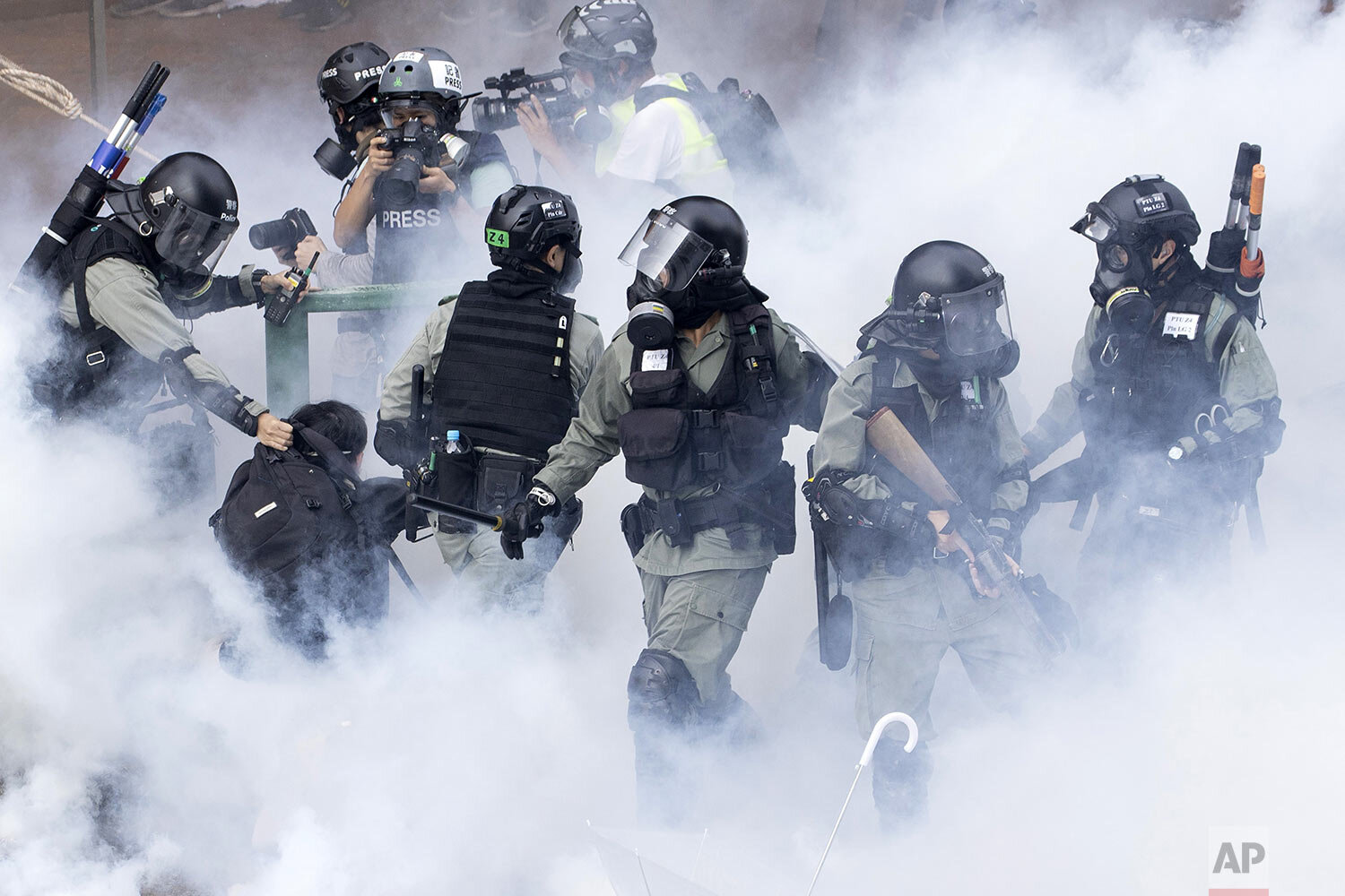  Police in riot gear move through a cloud of smoke as they detain a protester at the Hong Kong Polytechnic University in Hong Kong, Monday, Nov. 18, 2019. Hong Kong police fought off protesters with tear gas and batons Monday as they tried to break t