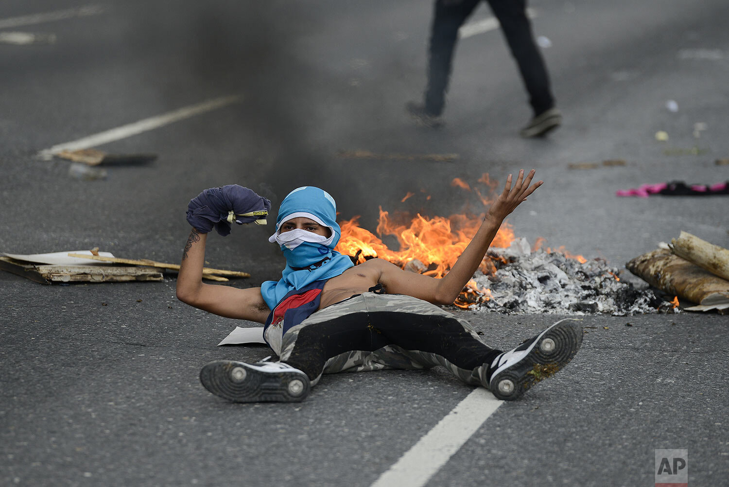  An anti-government protester lies in front of a burning barricade in an attempt to block traffic, in Caracas, Venezuela, Saturday, Nov. 16, 2019. Opposition politician Juan Guaido called nationwide demonstrations to re-ignite a campaign against Pres