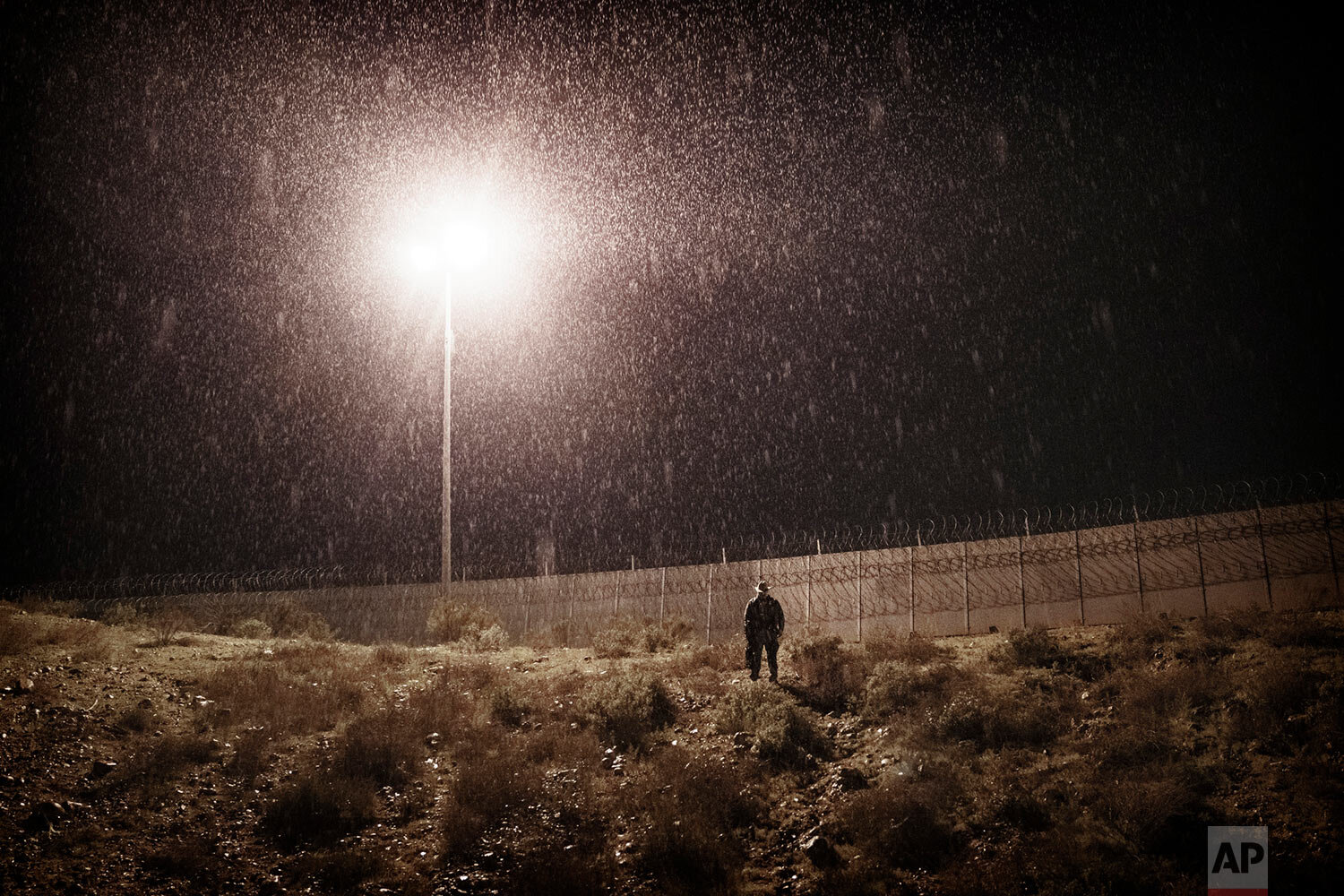  A U.S. Border Protection officer stands in heavy rain near the border fence between San Diego, Calif., and Tijuana, Mexico, on Jan. 1, 2019. (AP Photo/Daniel Ochoa de Olza) 