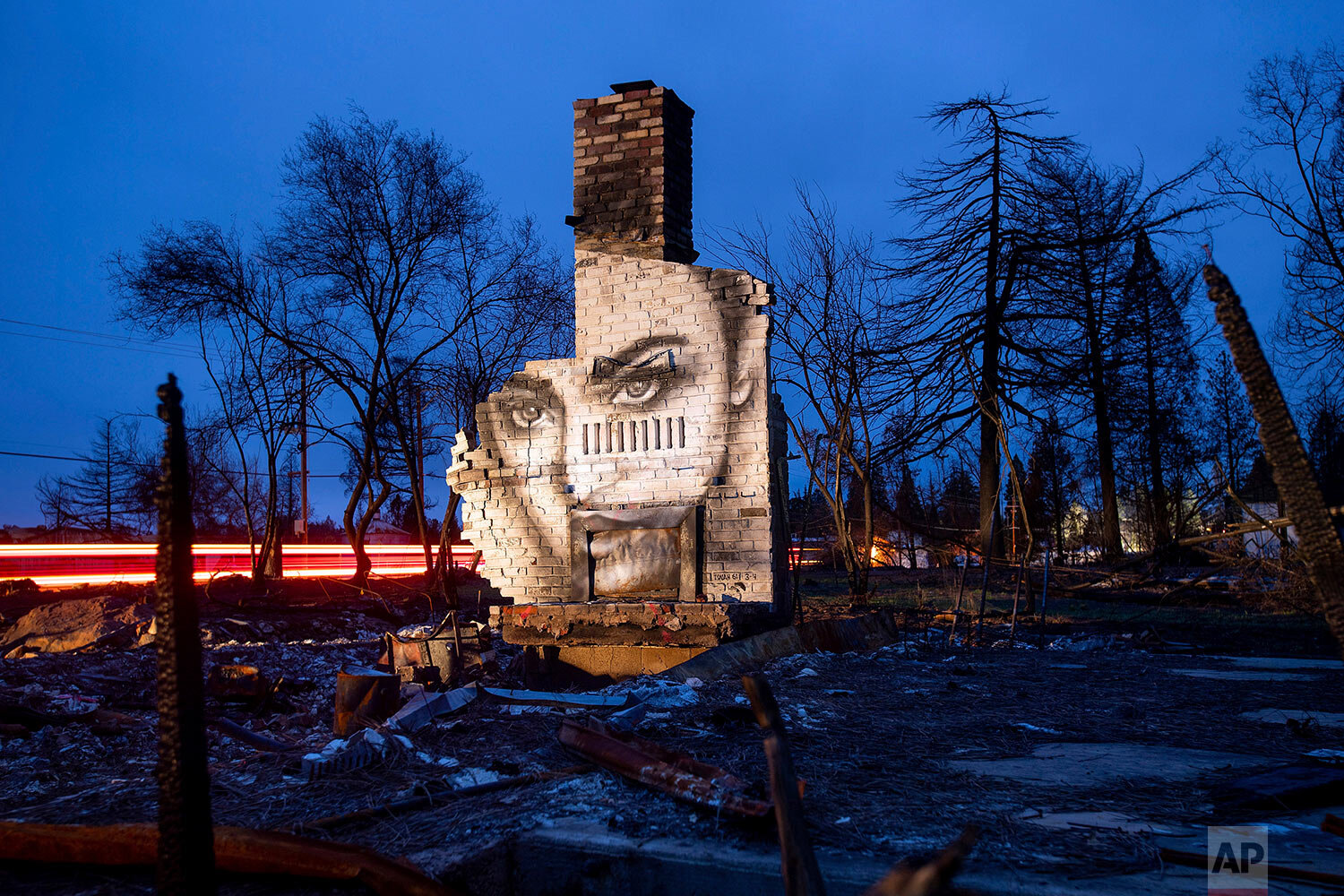  A mural is illuminated at dusk on Feb. 8, 2019, on the chimney of a home in Paradise, Calif., that was destroyed by the Camp Fire. Artist Shane Grammer says he painted murals throughout the fire-ravaged town to convey hope in the midst of destructio