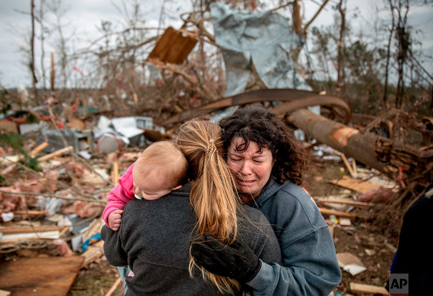  Carol Dean, right, cries and embraces Megan Anderson and her 18-month-old daughter, Madilyn, as Dean sifts through the debris of the home she shared with her husband, David Wayne Dean, who died when a tornado destroyed the house in Beauregard, Ala.,