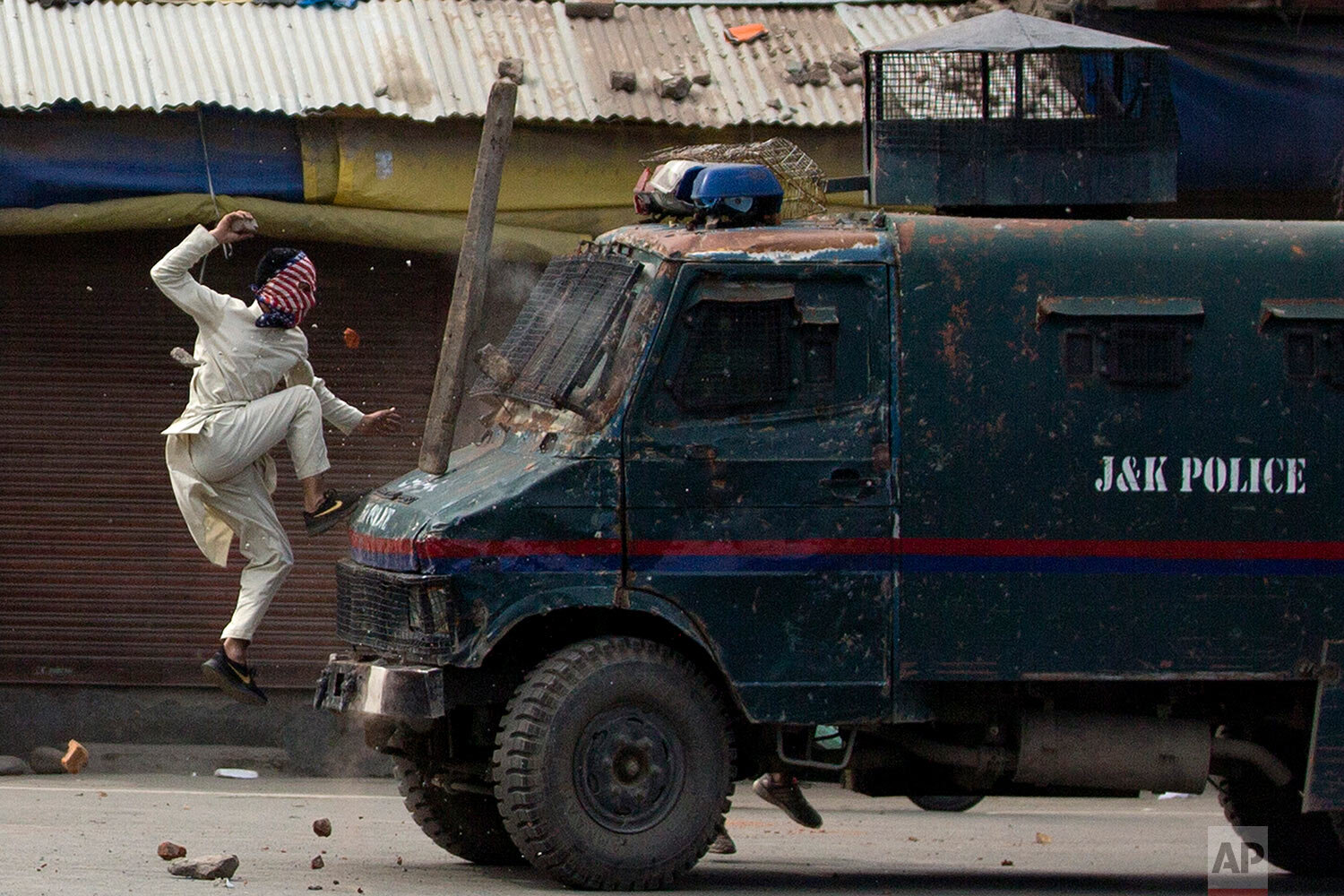 A masked Kashmiri protester jumps on an Indian police armored vehicle as he throws stones at it during a protest in Srinagar, Indian-controlled Kashmir on May 31, 2019. (AP Photo/Dar Yasin) 
