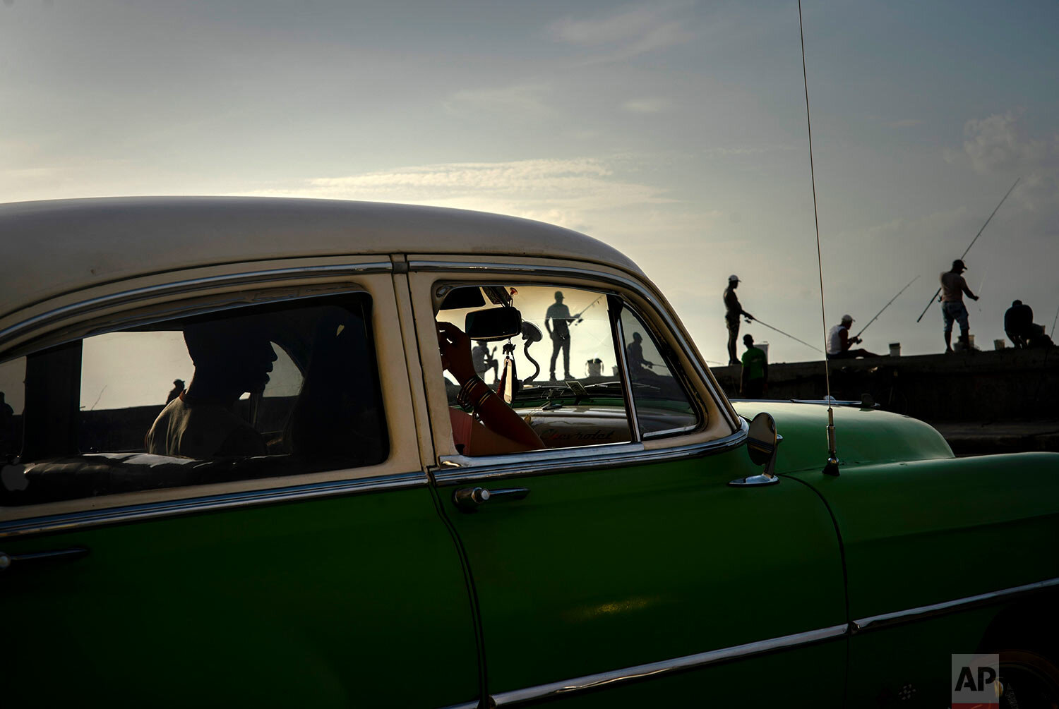  A couple in a classic American car drive past fishermen along the Malecon seawall at sunset in Havana, Cuba, on June 19, 2019. (AP Photo/Ramon Espinosa) 