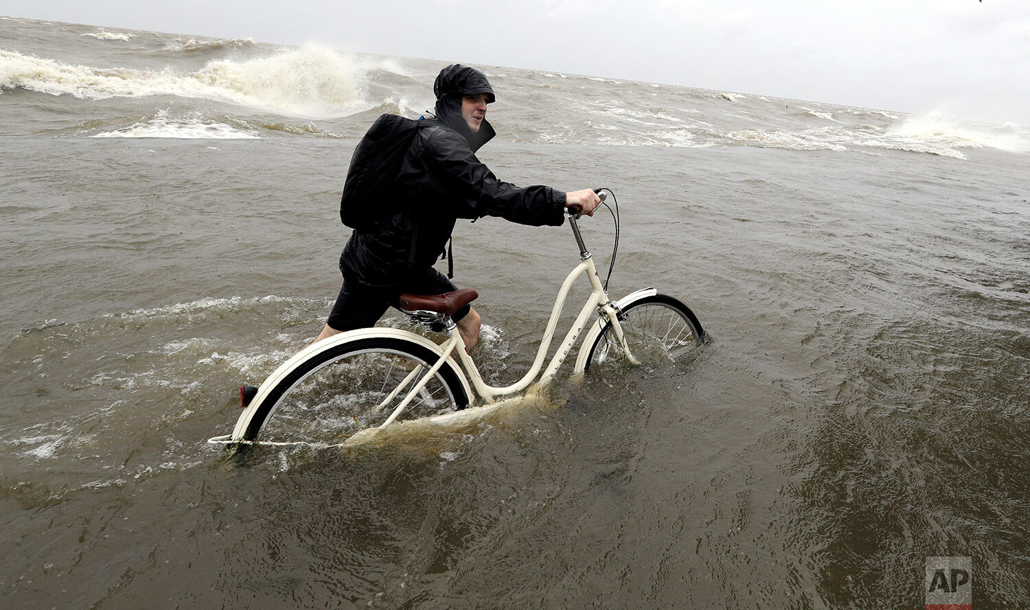  Tyler Holland guides his bike through the water as winds from Tropical Storm Barry push water from Lake Pontchartrain over the seawall in Mandeville, La., on July 13, 2019. (AP Photo/David J. Phillip) 