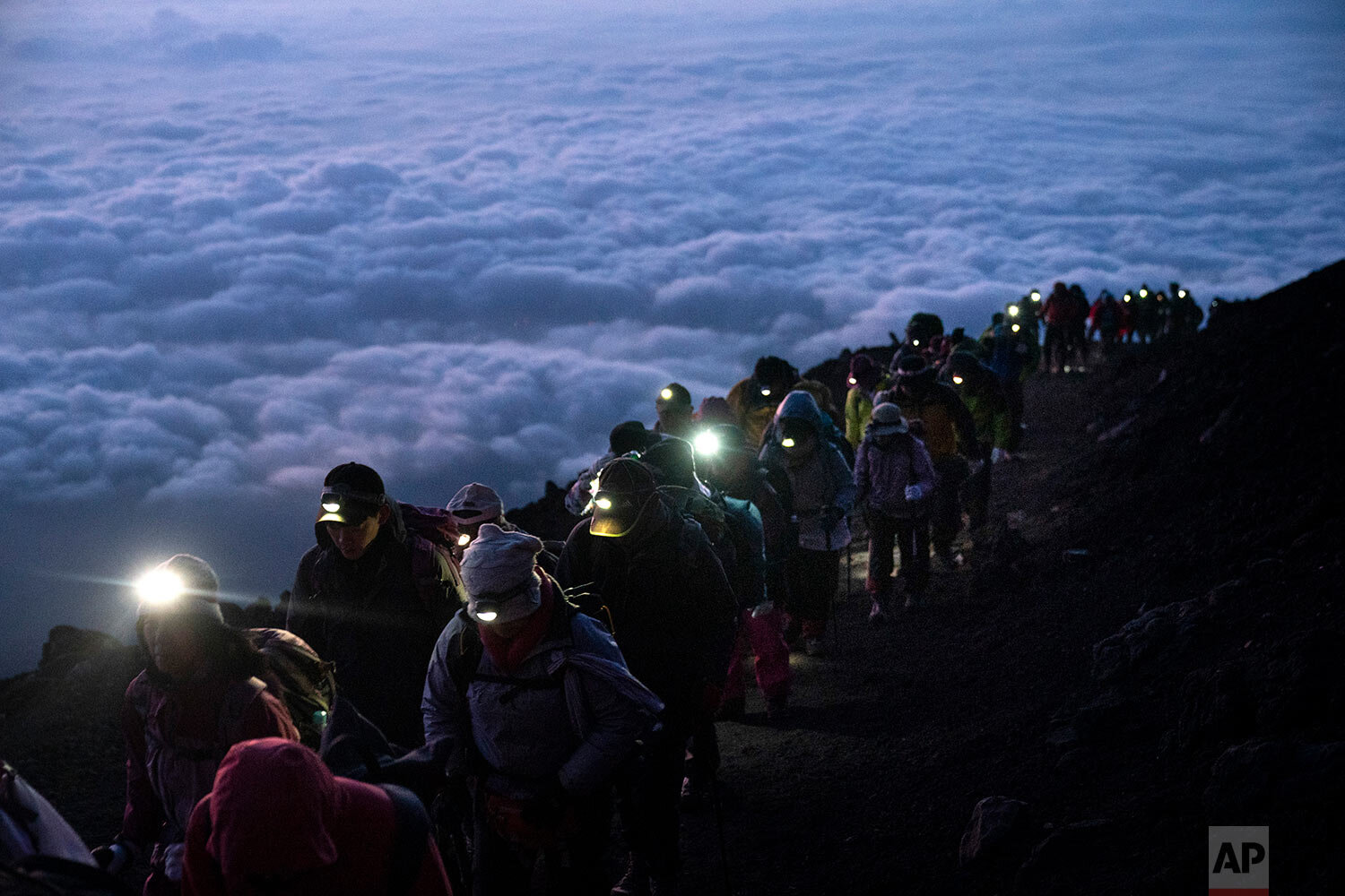  A group of climbers make their way to the summit of Japan's Mount Fuji, above a layer of clouds, to watch the sunrise on Aug. 27, 2019. (AP Photo/Jae C. Hong) 