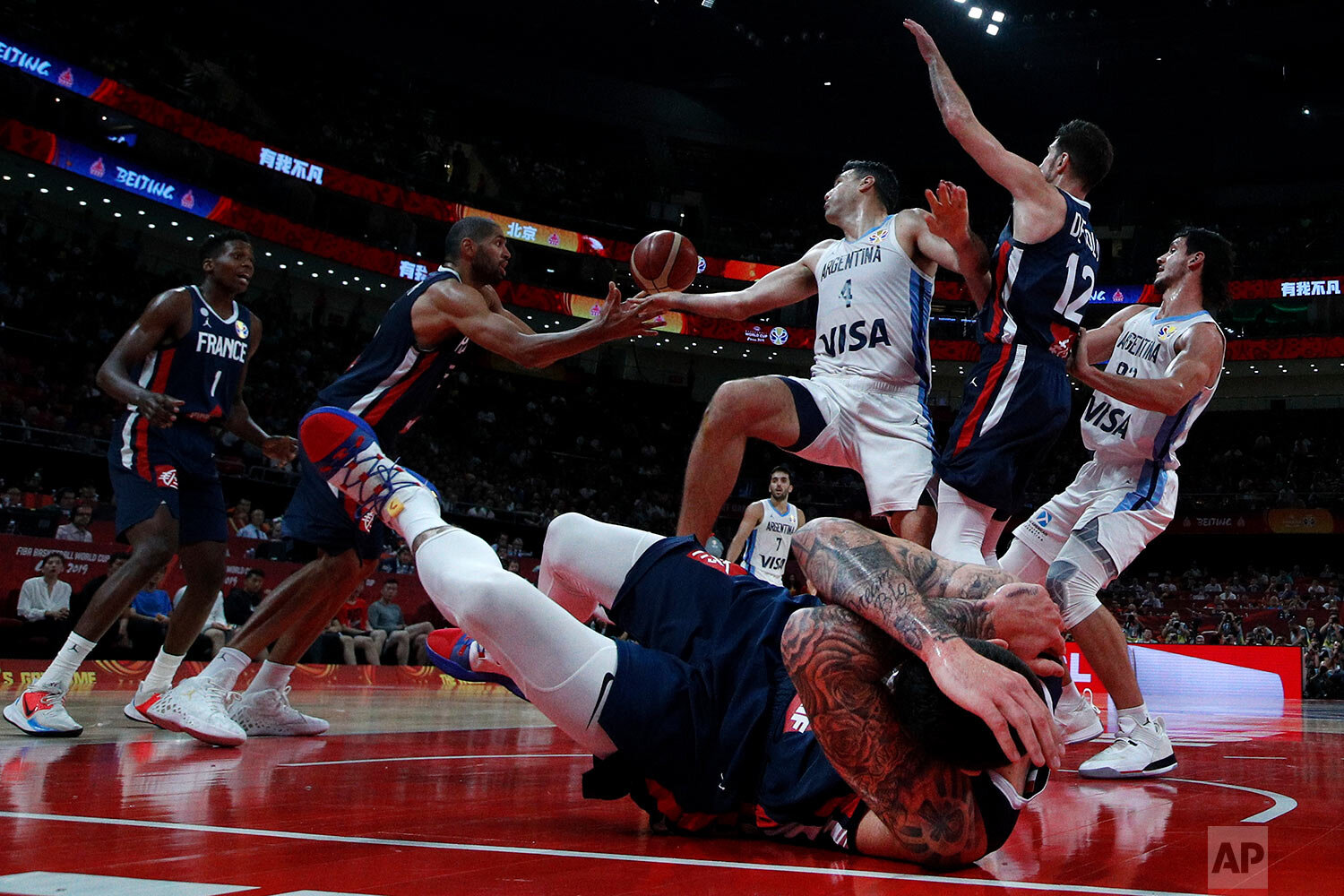  Vincent Poirier of France falls on the court as Luis Scola of Argentina fights for the ball with Nicholas Batum, second from left, during their semifinals match for the FIBA Basketball World Cup at the Cadillac Arena in Beijing on Sept. 13, 2019. (A