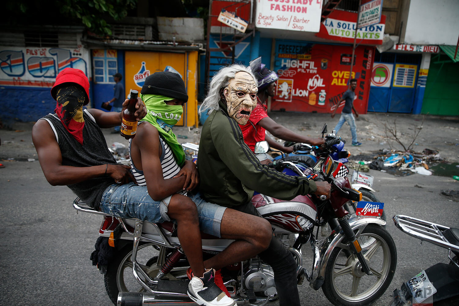  Masked protestors ride a motorcycle on Sept. 30, 2019, in Port-au-Prince, Haiti, where demonstrators set fires and called for Haiti's President Jovenel Moise to resign. (AP Photo/Rebecca Blackwell) 