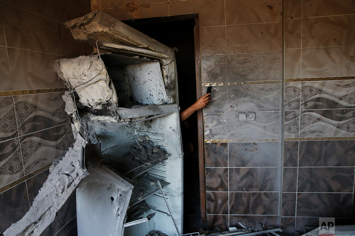  A local resident uses his mobile phone to take photos of the damage in a house caused by a mortar fired from inside Syria on the Turkish town of Akcakale on Oct. 12, 2019. (AP Photo/Lefteris Pitarakis) 